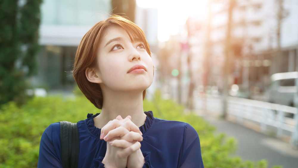 空に向かって祈る女性