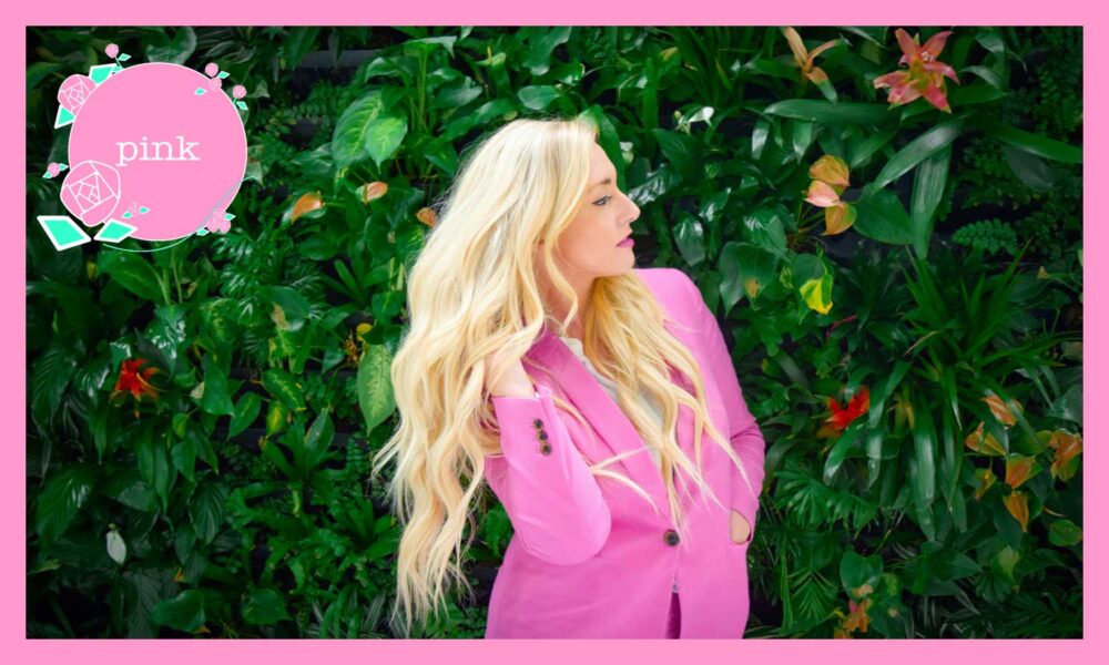 ピンク色のジャケットを着て立っている、金髪の女性の横顔