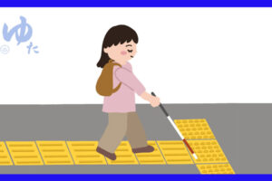 白杖を使って点字ブロックの上を歩く女性
