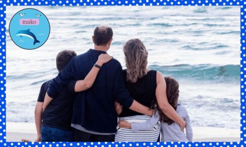 肩を抱き合いながら海を見る家族