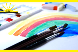 虹の絵と絵筆や絵の具、パレットの写真