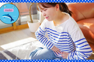お腹の痛みに耐えながらおなかを押さえている女性