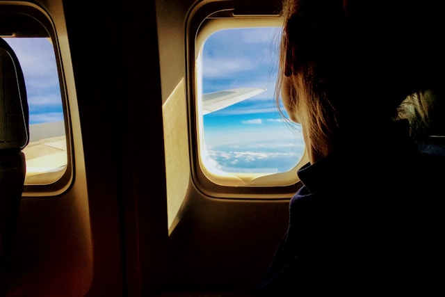 飛行機の窓から外を眺める女性