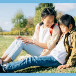 芝生に座っている小学生の男女