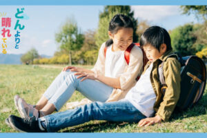 芝生に座っている小学生の男女