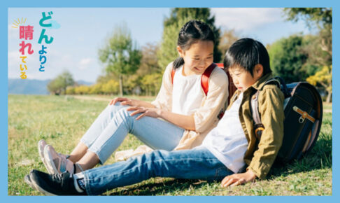 芝生に座っている小学生の男女