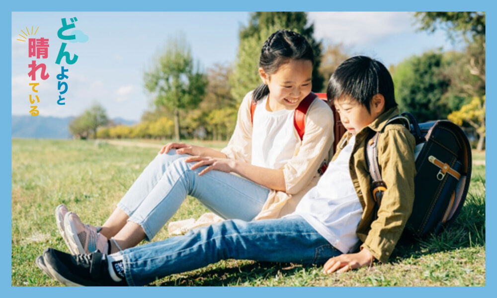 芝生に座っている小学生の男女