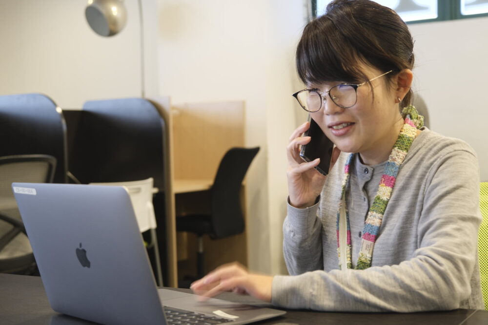 パソコンの前で電話をする女性