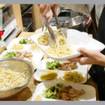 ご飯をトングで取り分ける女性