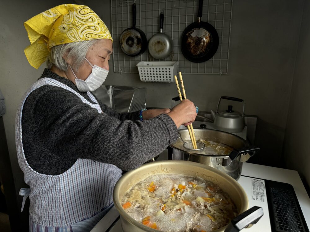 高齢女性が豚汁を作っている