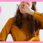外した眼鏡を片手に持ち、その手で両目を押さえている女性