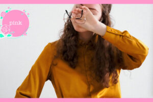 外した眼鏡を片手に持ち、その手で両目を押さえている女性