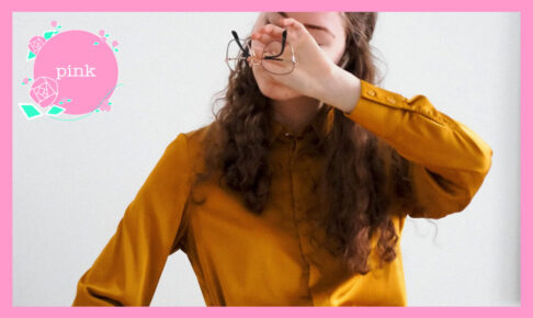 外した眼鏡を片手に持ち、その手で両目を押さえている女性