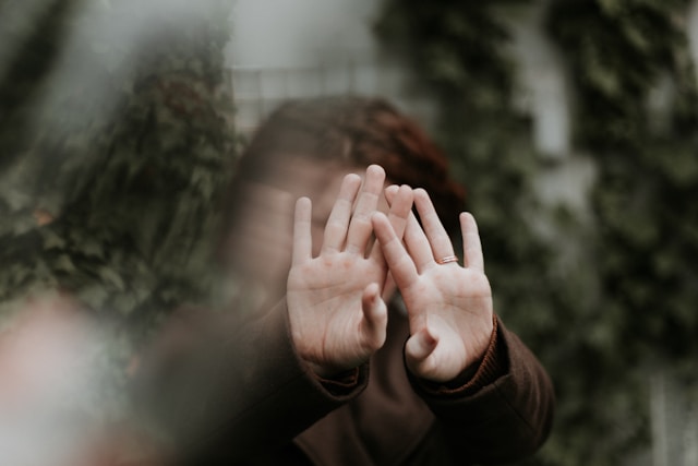 両手の手のひらを顔の前に出して、拒絶している女性