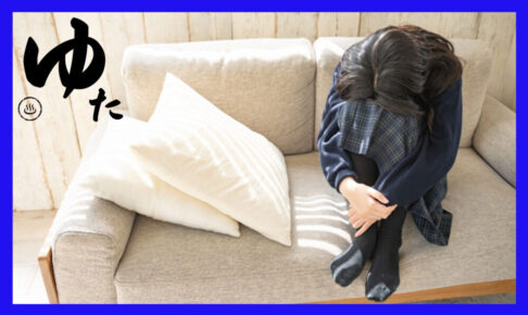 ソファーの上で膝を抱え、落ち込んでいる女子高校生