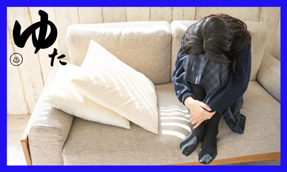 ソファーの上で膝を抱え、落ち込んでいる女子高校生