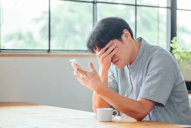 スマホを見て絶望する男性