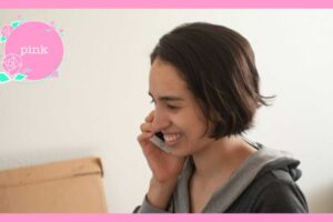 右手にスマートフォンを持って、笑顔で話をしている女性