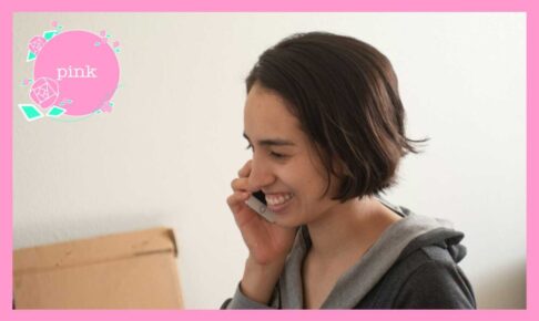 右手にスマートフォンを持って、笑顔で話をしている女性