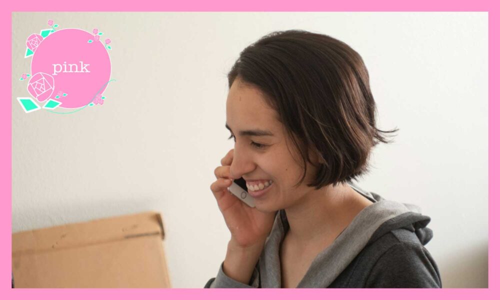 右手にスマートフォンを持って、笑顔で話をしている女性
