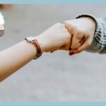 黒と白の長袖のシャツを着た人が茶色のコートの女性と手をつないでいる