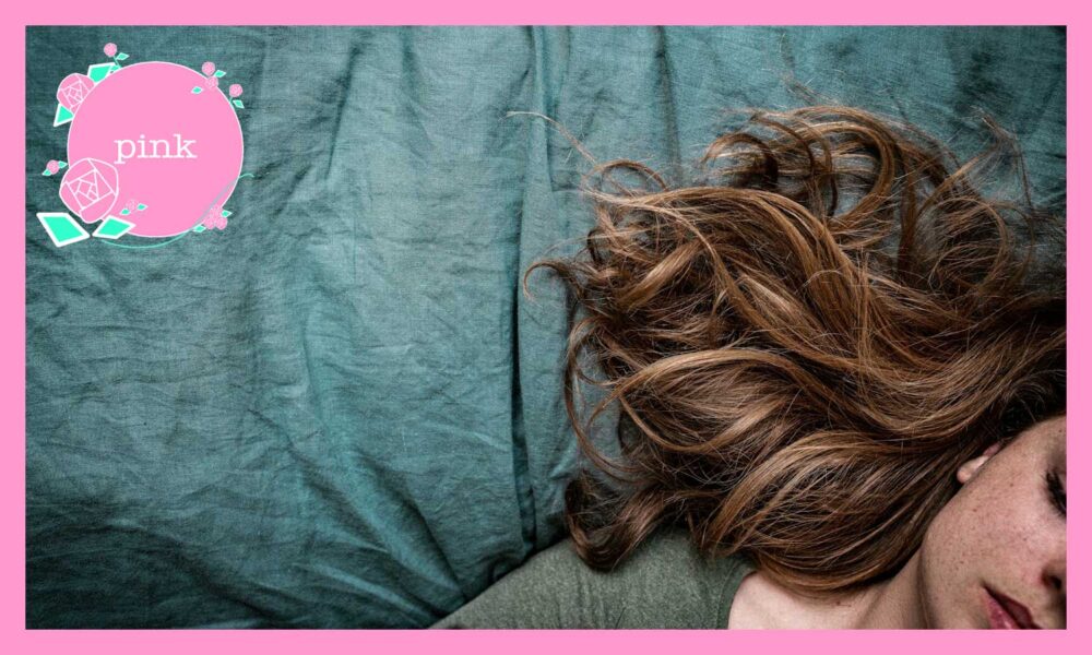 シーツの上に、目を閉じて横たわる女性