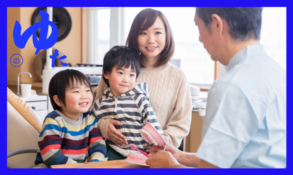 歯医者の先生に歯の治療について説明を受ける二人の男の子とそのお母さん