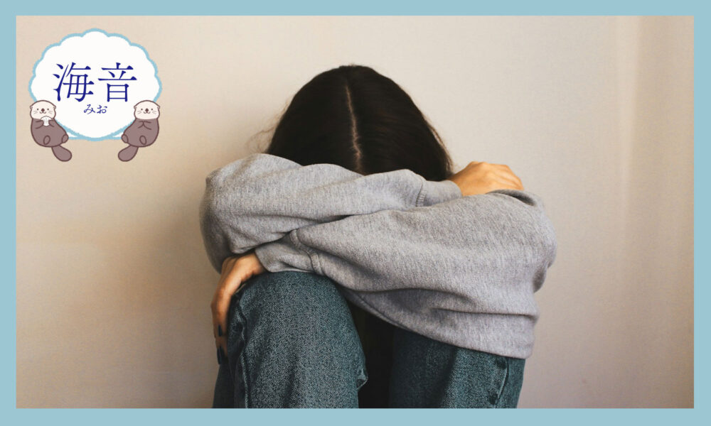 腕を頭に巻き付けて床に座っている女性