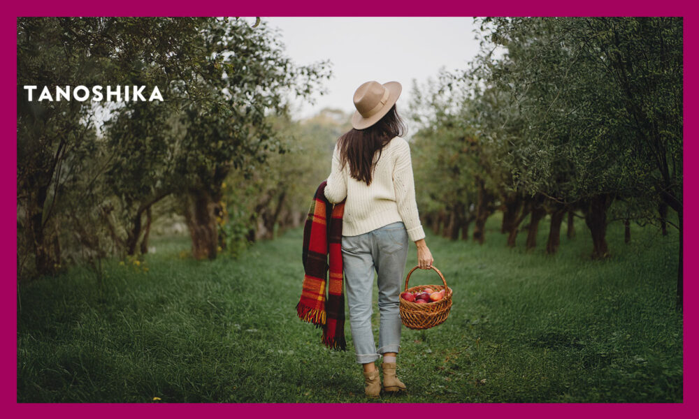 リンゴの木の中を歩く女性