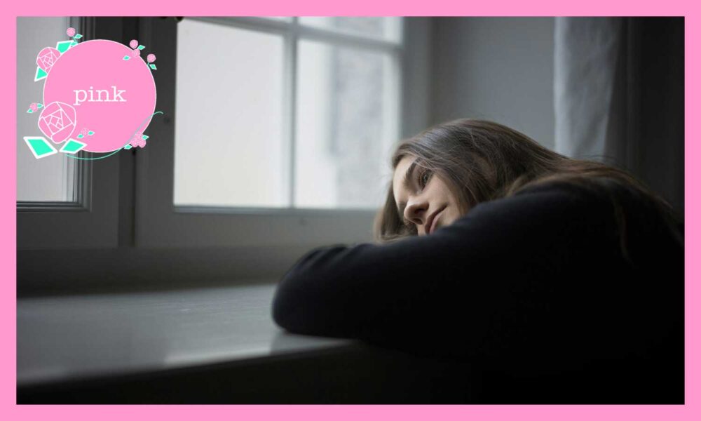 窓際の机にうつぶせになっている、髪の長い女性