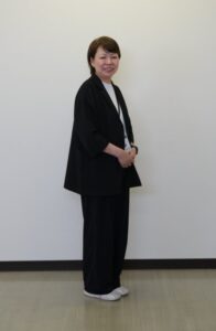 オフィスの壁を背景に立つ女性