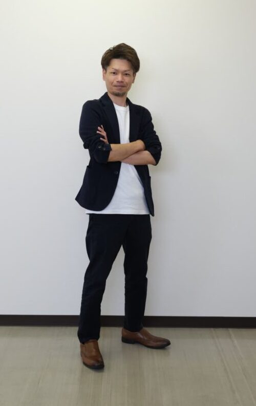 腕を組んで立つ久保田さん