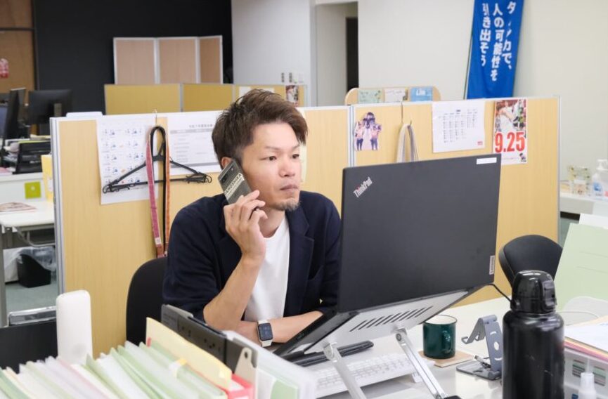 パソコンの前で仕事の電話をしている久保田さん