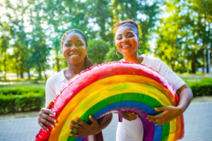 LGBTQの旗を持つ、笑顔の女性二人