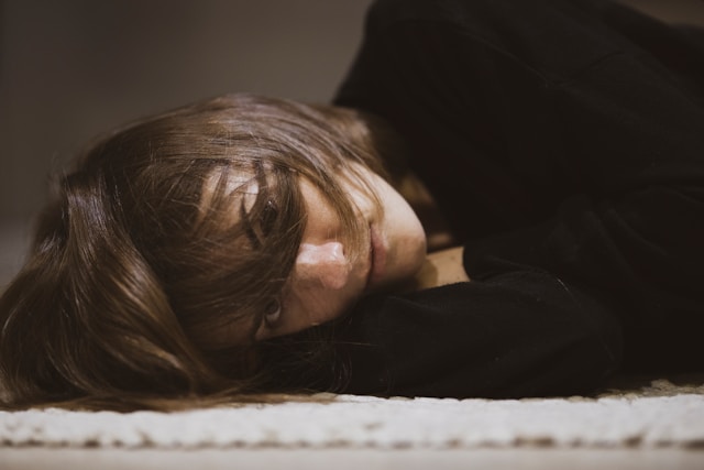 白い布地に横たわる黒い長袖シャツの女性
