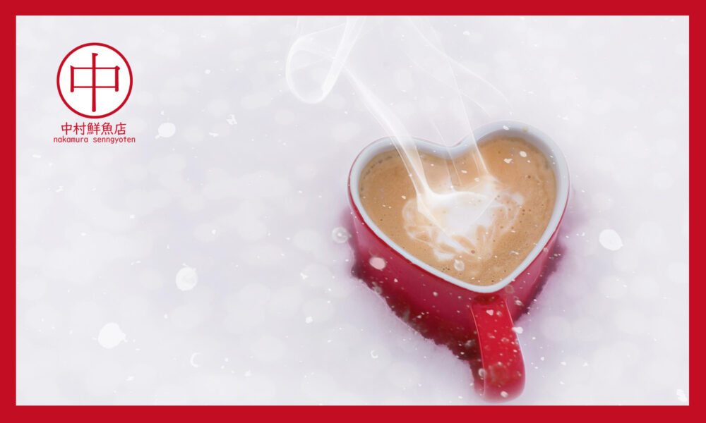 雪に埋まった赤いハートの温かい飲み物の入ったマグカップ