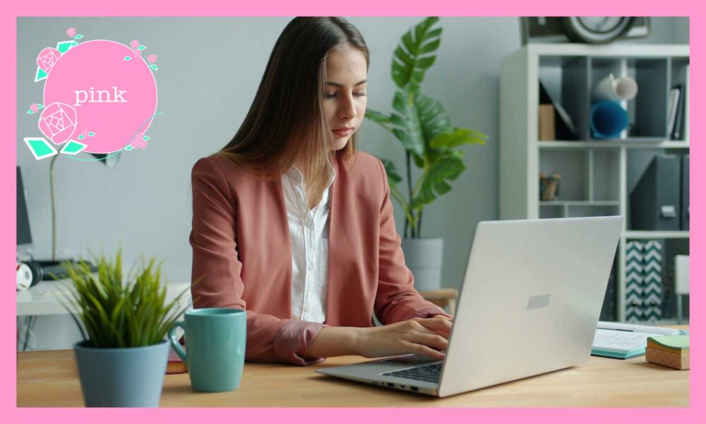 椅子に座り、ノートパソコンで仕事をしているジャケットを着た女性