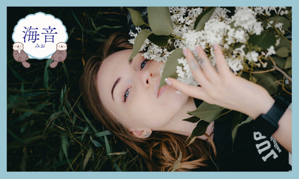 緑の芝生に横たわる花束を持った女性