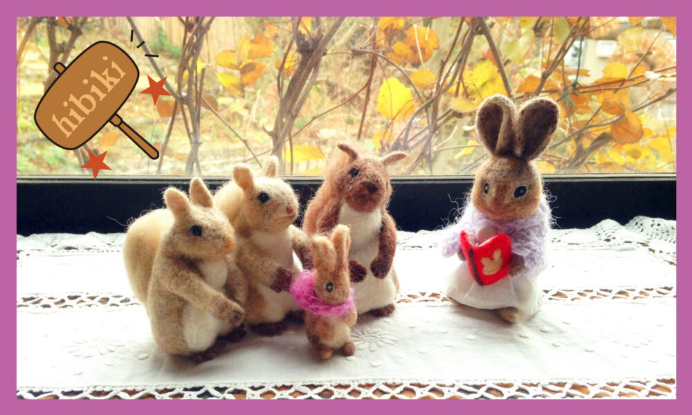 うさぎのぬいぐるみが、こうさぎのぬいぐるみに絵本を読んで聞かせている。