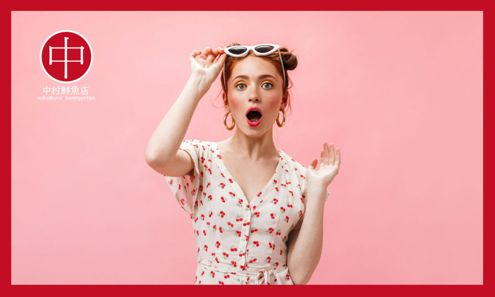 ピンクの背景にサングラスをずらして驚く外国の女性