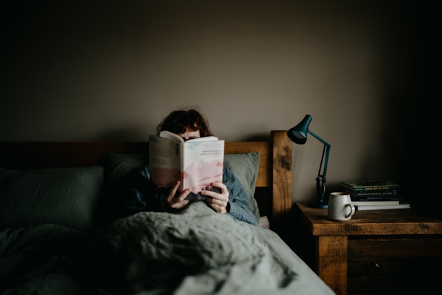 ベットに入って、本を読んでいる女性
