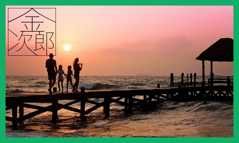 夕日の海の桟橋でたたずむ親子