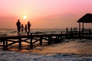 夕日の海の桟橋でたたずむ親子