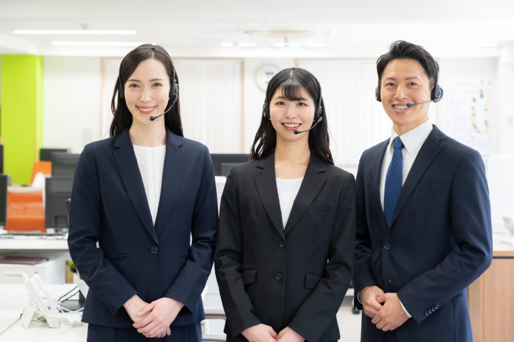 コールセンターの女性2人と男性１人が笑っている。