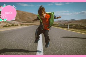 道路の真ん中の白線の上をまたいでジャンプしている男の子