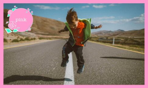 道路の真ん中の白線の上をまたいでジャンプしている男の子