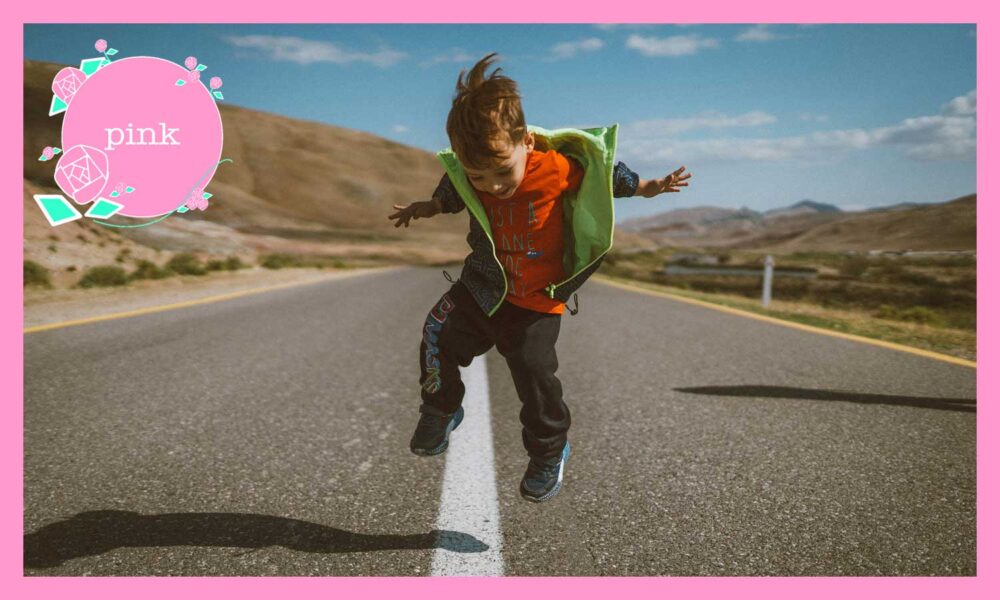 道路の真ん中の白線の上をまたいでジャンプしている男の子