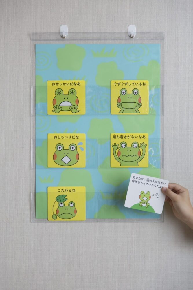6匹のかえるが描かれたカードの1枚を取る人