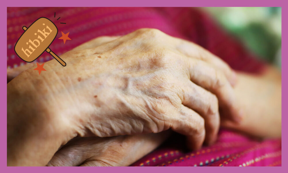 女性の年配の手を若い方が握り合っている。