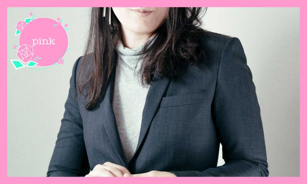 ハイネックにスーツのジャケットを着ている女性